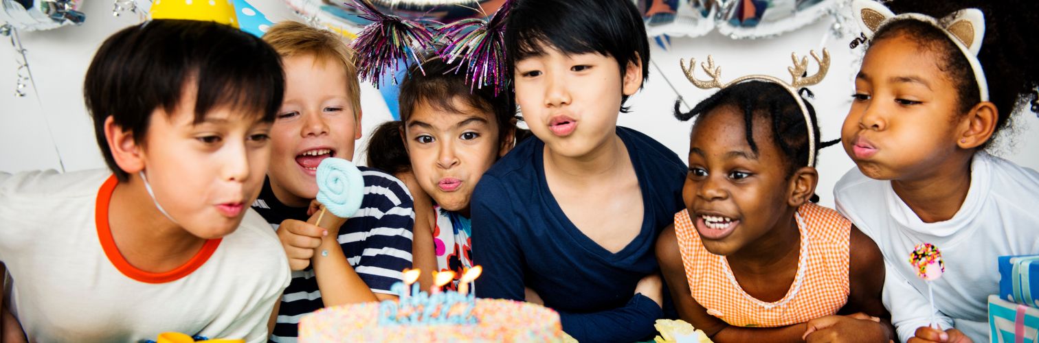 Six children blowing out birthday cake candles